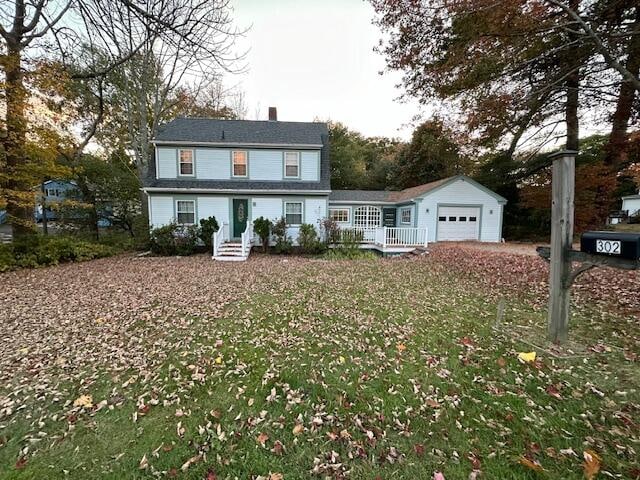 view of front of house with an outdoor structure, a front yard, covered porch, and a garage