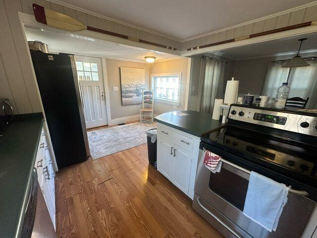 kitchen with black refrigerator, wood-type flooring, crown molding, electric range, and white cabinets