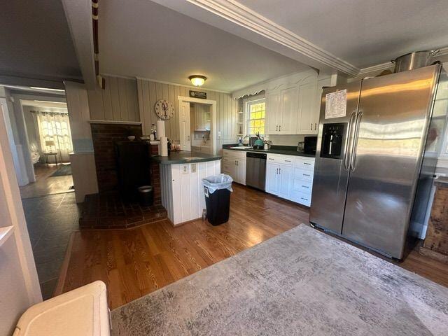 kitchen featuring white cabinets, beam ceiling, dark hardwood / wood-style flooring, crown molding, and stainless steel appliances