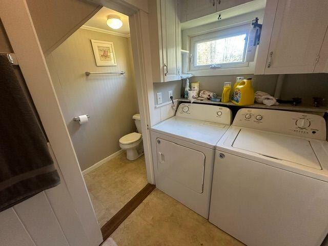 washroom featuring ornamental molding, washing machine and dryer, and cabinets