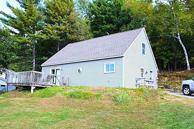 view of property exterior featuring a yard, a deck, and a shingled roof