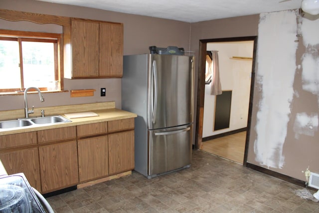 kitchen featuring freestanding refrigerator, light countertops, and a sink