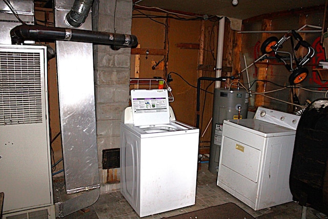 clothes washing area featuring washer and dryer, water heater, a heating unit, and laundry area