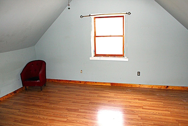 additional living space featuring baseboards, light wood-type flooring, and vaulted ceiling