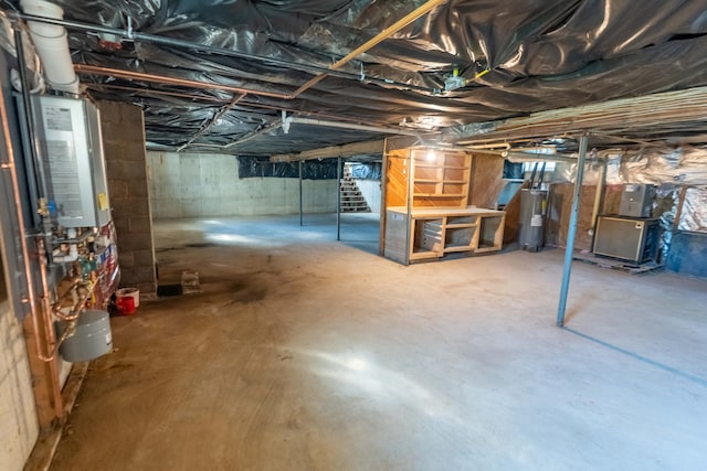 954 Mason Bay Rd, Jonesport, ME 04649 - unfinished below grade area with electric water heater, stairway, and tankless water heater