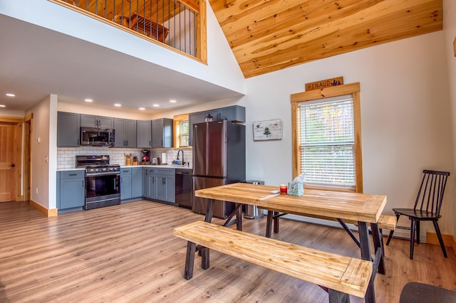 kitchen featuring sink, backsplash, light hardwood / wood-style floors, gray cabinets, and appliances with stainless steel finishes