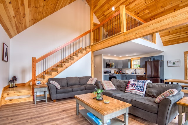 living room featuring light hardwood / wood-style floors, high vaulted ceiling, wooden ceiling, and sink