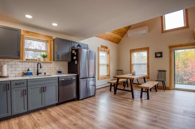 kitchen featuring appliances with stainless steel finishes, a wall unit AC, plenty of natural light, and sink