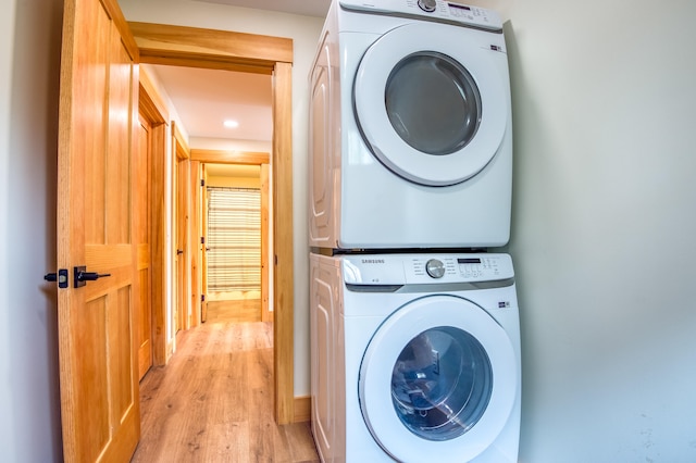 clothes washing area featuring stacked washing maching and dryer and light hardwood / wood-style floors