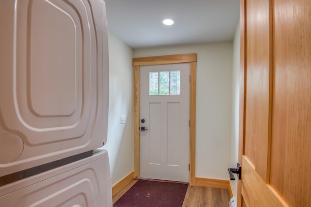 doorway with stacked washer and dryer and hardwood / wood-style floors