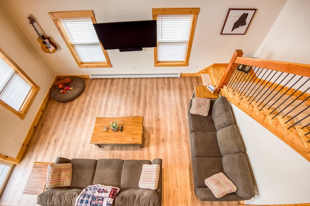 living room with baseboard heating, a wealth of natural light, and hardwood / wood-style floors