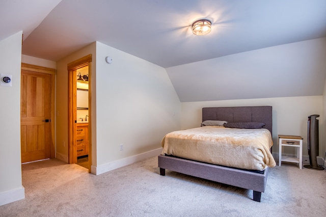 bedroom with lofted ceiling, light carpet, and connected bathroom