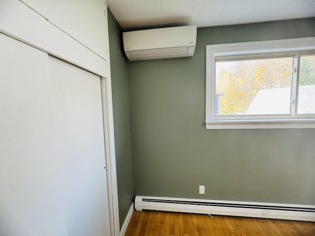 376 Fort Fairfield Rd, Caribou, ME 04736 - unfurnished bedroom with an AC wall unit, a baseboard heating unit, and wood finished floors