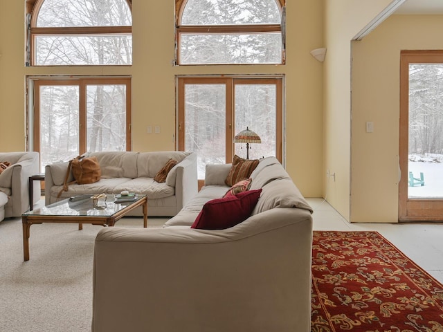 living room featuring a towering ceiling, light colored carpet, and a healthy amount of sunlight