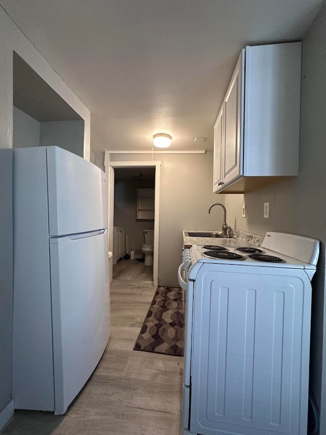 kitchen with sink, white cabinetry, white refrigerator, and washer / dryer