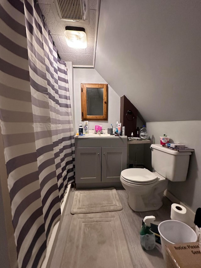 bathroom with curtained shower, toilet, vanity, and lofted ceiling