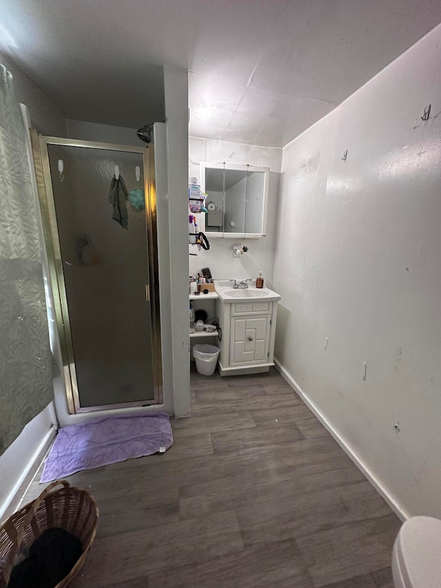 bathroom featuring hardwood / wood-style floors, toilet, a shower with door, and vanity