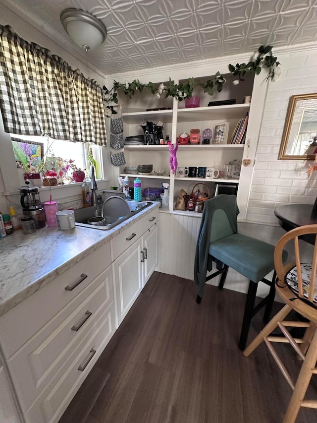 kitchen with white cabinets, dark wood-type flooring, sink, and light stone counters