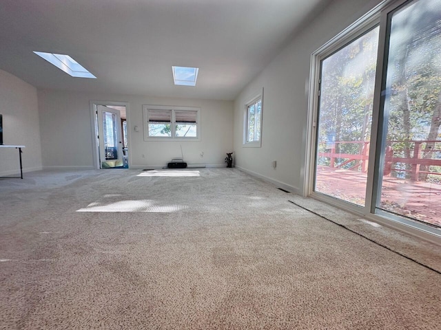 interior space with carpet floors, lofted ceiling with skylight, and baseboards