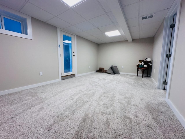 carpeted empty room with baseboards, visible vents, and a drop ceiling