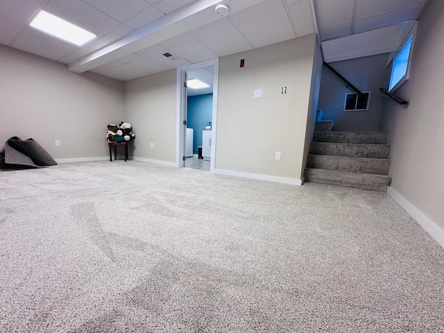 finished basement with carpet floors, stairway, washer and dryer, a drop ceiling, and baseboards