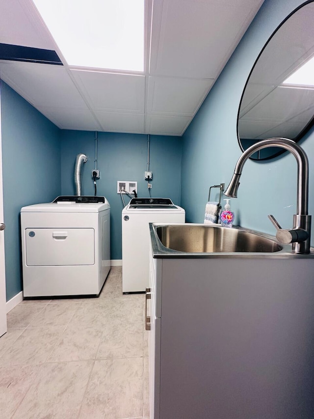 laundry area featuring laundry area, washer and clothes dryer, a sink, and baseboards