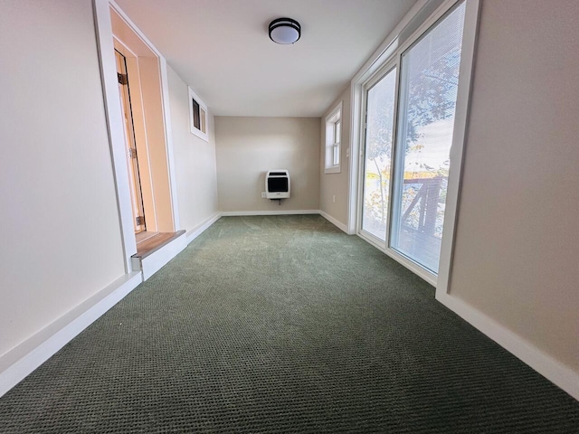 empty room featuring heating unit, carpet, and baseboards