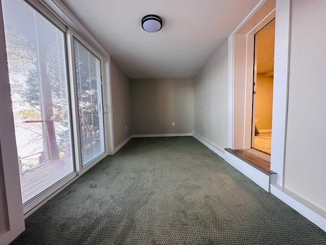 spare room featuring dark carpet and baseboards