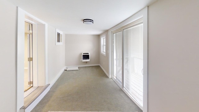 corridor featuring heating unit, baseboards, and light colored carpet