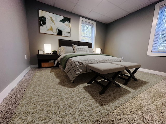 bedroom with carpet flooring, a paneled ceiling, and baseboards