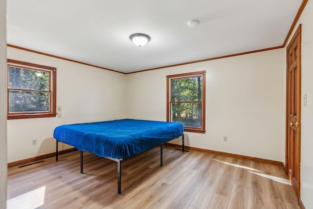 bedroom with crown molding and light wood-type flooring