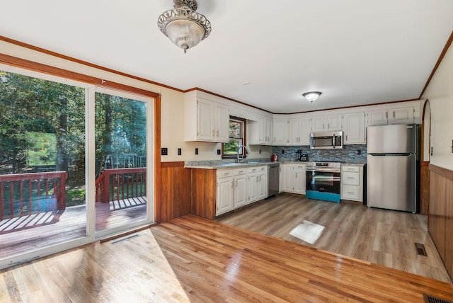 kitchen featuring stainless steel appliances, plenty of natural light, white cabinets, and light hardwood / wood-style flooring