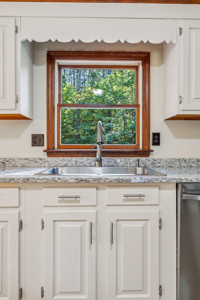 kitchen with stainless steel dishwasher, white cabinets, sink, and a wealth of natural light