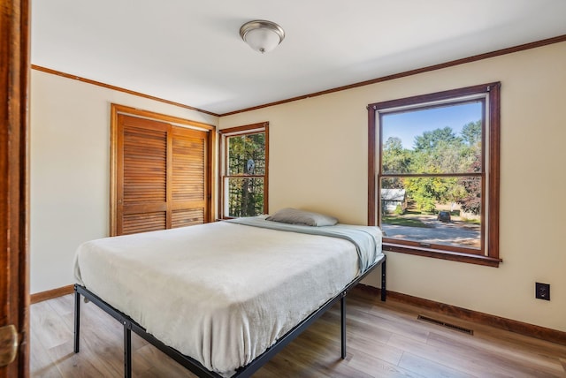 bedroom featuring hardwood / wood-style flooring, a closet, and crown molding