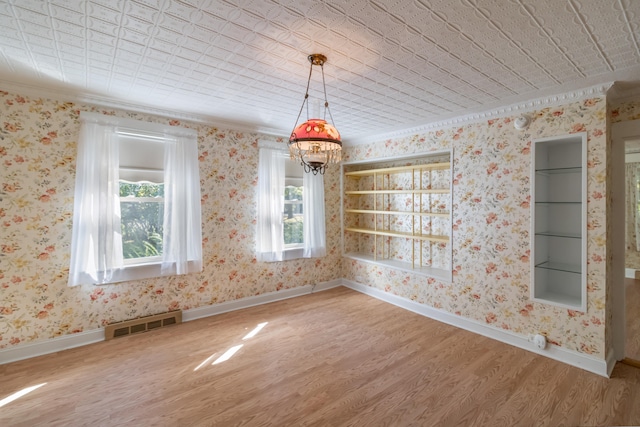 unfurnished dining area featuring ornamental molding, a notable chandelier, hardwood / wood-style floors, and a healthy amount of sunlight