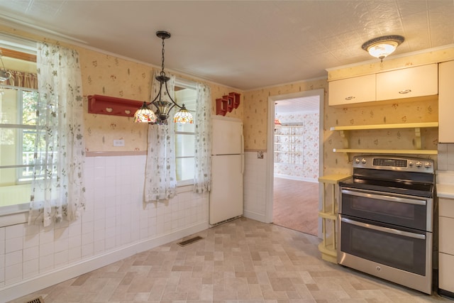 kitchen featuring pendant lighting, plenty of natural light, white refrigerator, and stainless steel electric range