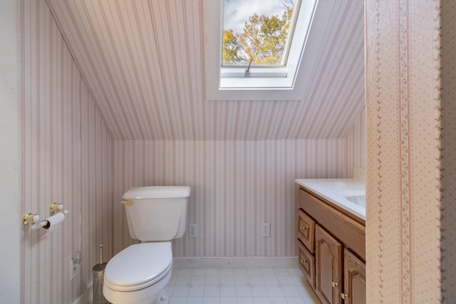 bathroom featuring lofted ceiling with skylight, vanity, and toilet