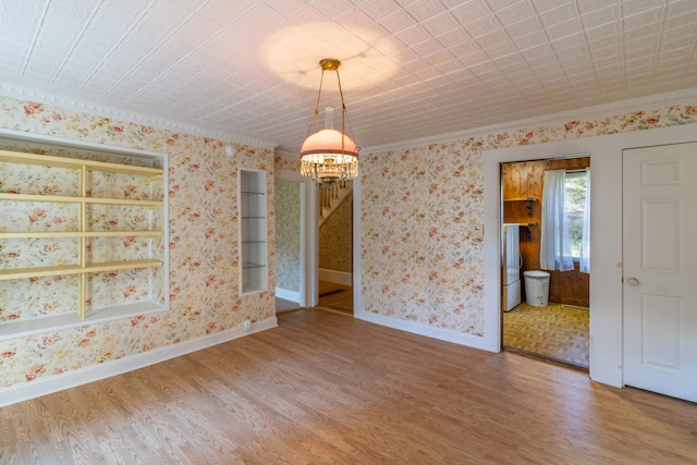 unfurnished dining area with wood-type flooring, crown molding, and an inviting chandelier