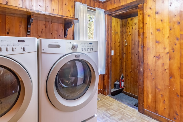 laundry room with separate washer and dryer, wooden walls, and light parquet floors