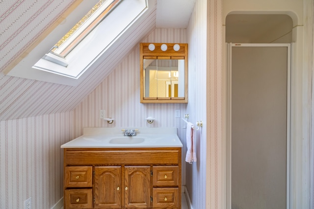 bathroom featuring walk in shower, vanity, and vaulted ceiling with skylight