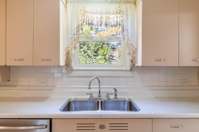 kitchen featuring stainless steel dishwasher, sink, and tasteful backsplash