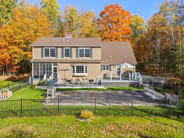 rear view of house with a wooden deck, a patio area, a sunroom, and a yard