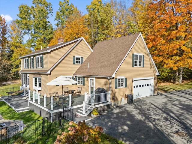 rear view of property featuring a wooden deck and a garage