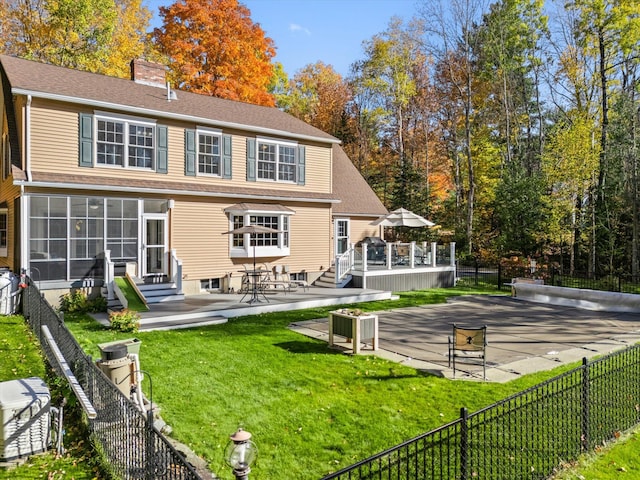 rear view of house with a wooden deck, a patio area, and a lawn