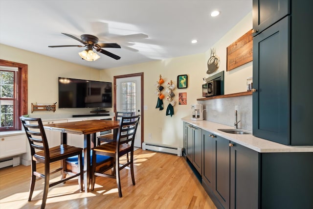 kitchen featuring tasteful backsplash, sink, ceiling fan, baseboard heating, and light hardwood / wood-style flooring