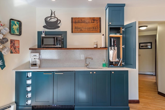 kitchen with blue cabinetry, sink, and light wood-type flooring