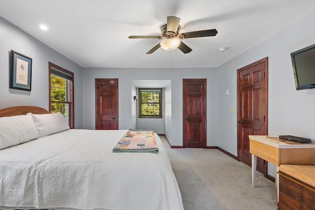 bedroom with multiple windows, light colored carpet, and ceiling fan