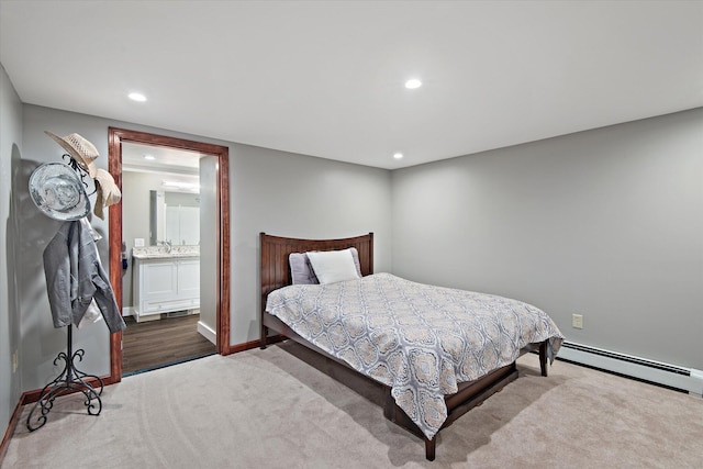 carpeted bedroom featuring ensuite bathroom and a baseboard heating unit