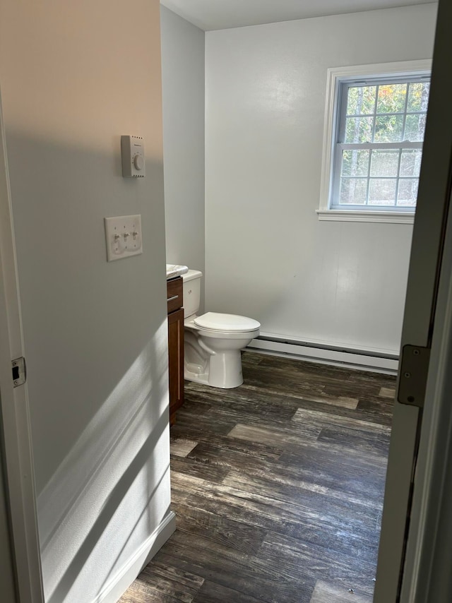 bathroom with hardwood / wood-style floors, a baseboard heating unit, vanity, and toilet