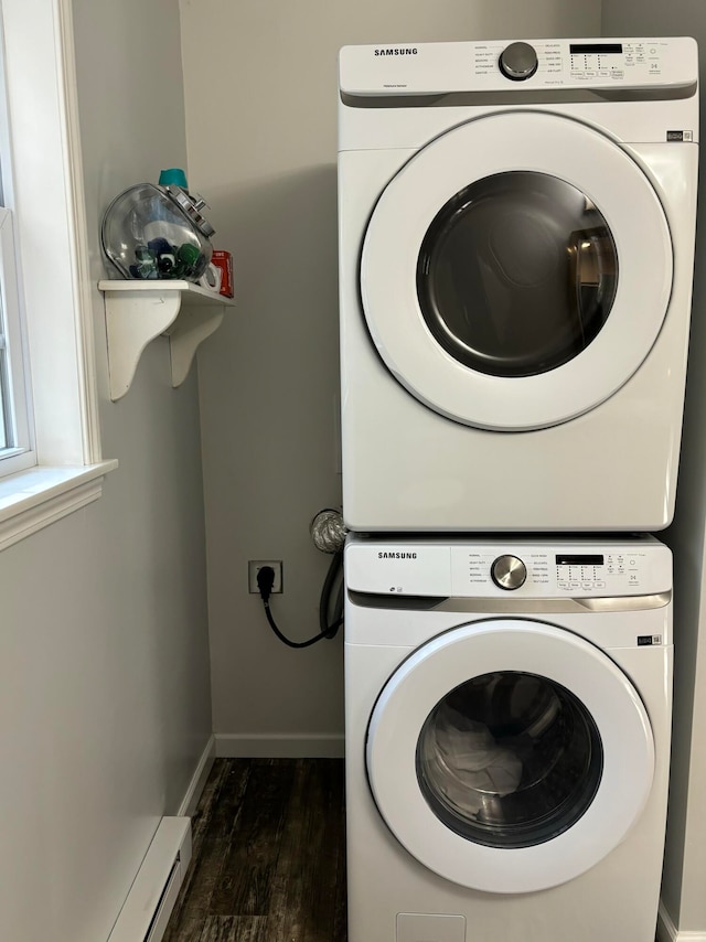 washroom with baseboard heating, dark hardwood / wood-style floors, and stacked washer / drying machine